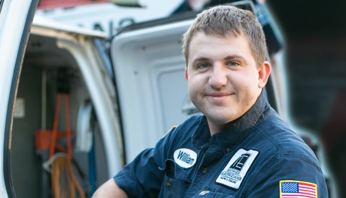 Smiling tech standing behind van with doors open